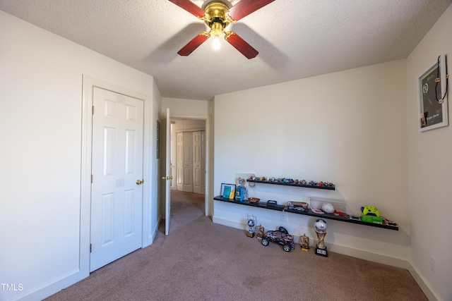 workout area featuring a textured ceiling, light colored carpet, and ceiling fan