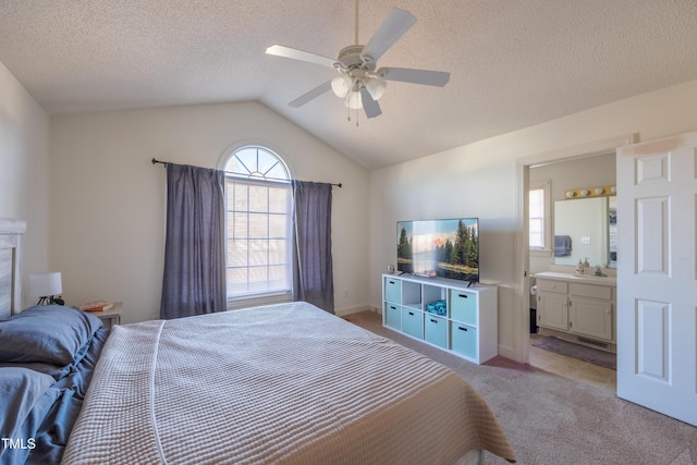 bedroom with ensuite bath, ceiling fan, light colored carpet, a textured ceiling, and vaulted ceiling