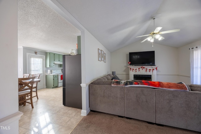 living room featuring ceiling fan, lofted ceiling, and a textured ceiling