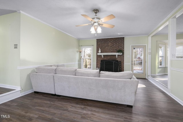 living room with crown molding, dark wood-type flooring, and a brick fireplace