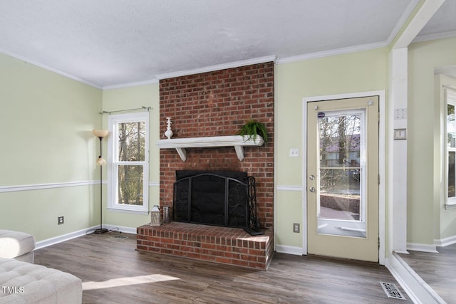 unfurnished living room featuring a textured ceiling, dark wood-type flooring, a brick fireplace, and crown molding