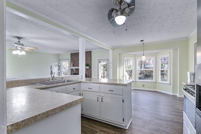 kitchen with white cabinetry, sink, a brick fireplace, white range, and crown molding