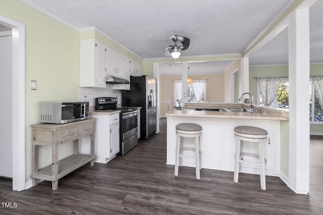 kitchen with kitchen peninsula, appliances with stainless steel finishes, a breakfast bar, sink, and white cabinets