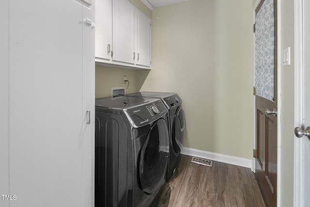 laundry area featuring washer and dryer, dark wood-type flooring, and cabinets