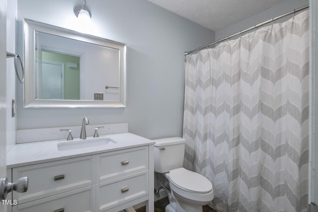 bathroom with vanity, toilet, a textured ceiling, and walk in shower