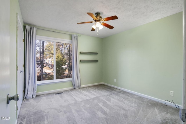 spare room featuring light carpet, ceiling fan, and a textured ceiling