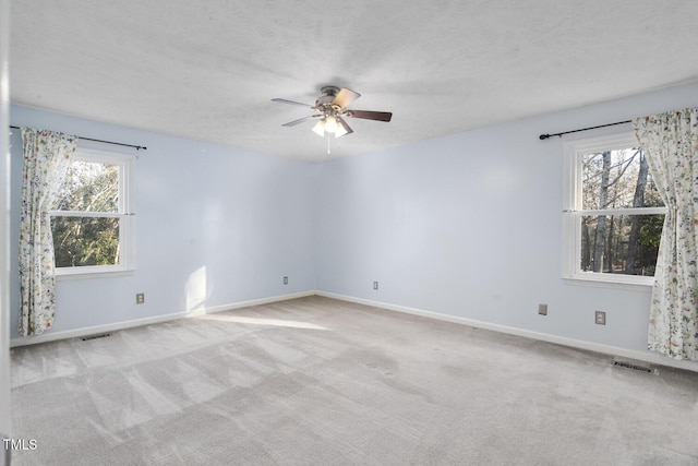 unfurnished room with ceiling fan, plenty of natural light, light colored carpet, and a textured ceiling