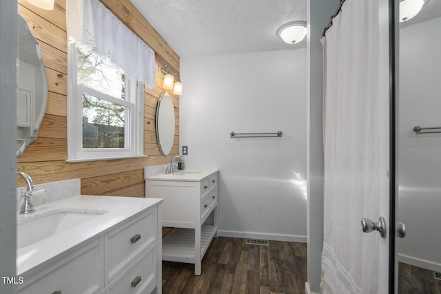 bathroom with wood walls, vanity, a textured ceiling, and hardwood / wood-style flooring