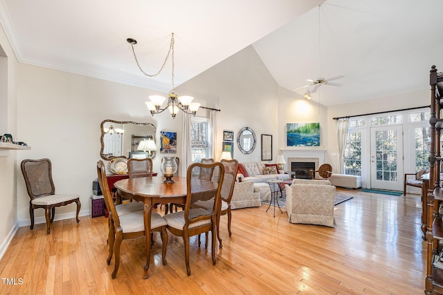 dining area featuring ceiling fan with notable chandelier, light hardwood / wood-style floors, and high vaulted ceiling