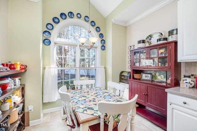 tiled dining area featuring ornamental molding, lofted ceiling, and a notable chandelier