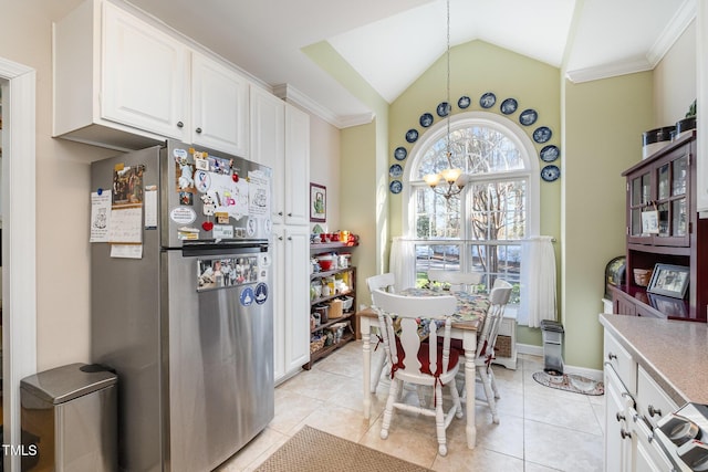 kitchen featuring lofted ceiling, white cabinets, stainless steel fridge, light tile patterned floors, and a notable chandelier