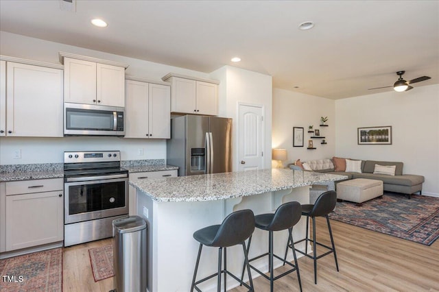 kitchen featuring light hardwood / wood-style floors, a breakfast bar, a center island, and stainless steel appliances