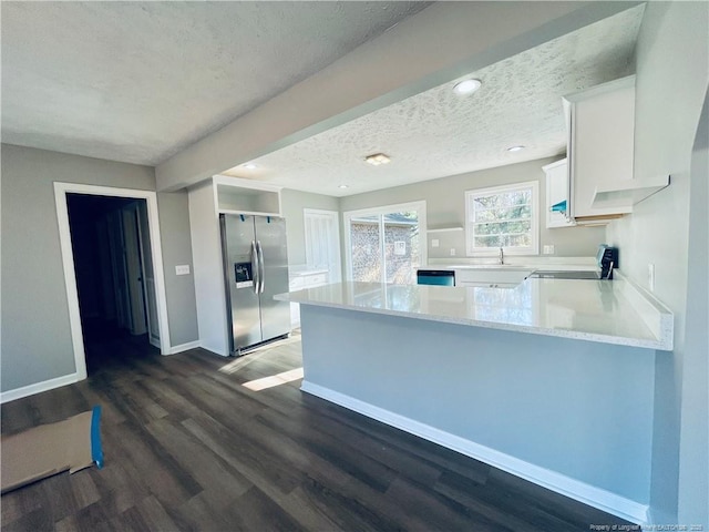 kitchen featuring dark hardwood / wood-style flooring, kitchen peninsula, stainless steel fridge, white cabinets, and range