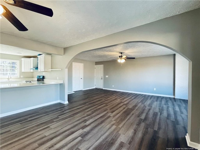 unfurnished living room featuring ceiling fan, dark hardwood / wood-style flooring, a textured ceiling, and sink