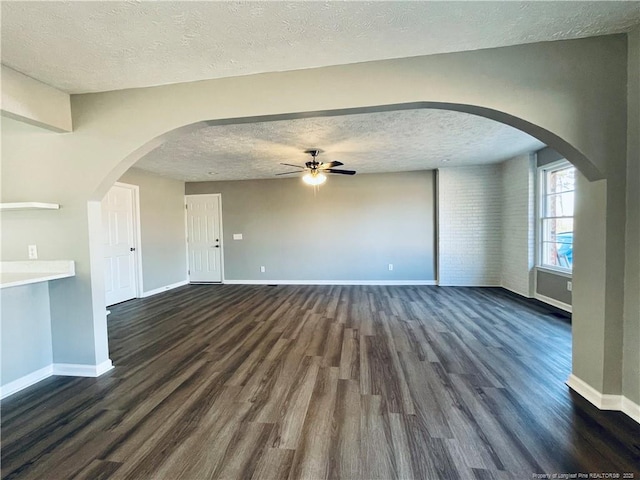 unfurnished living room with ceiling fan, a textured ceiling, and dark wood-type flooring