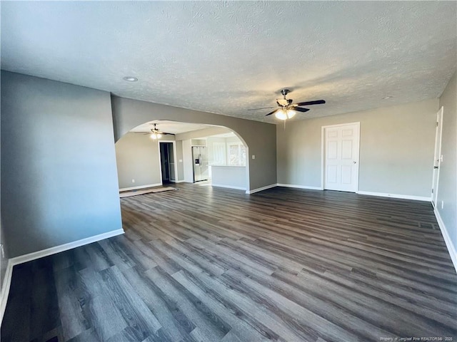 unfurnished living room with a textured ceiling, ceiling fan, and dark wood-type flooring