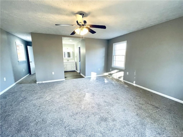 empty room with ceiling fan, dark carpet, and a textured ceiling