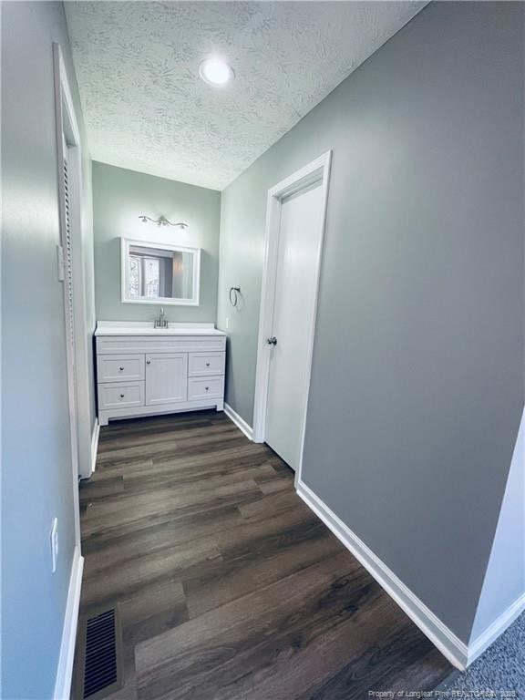 bathroom with hardwood / wood-style floors, vanity, and a textured ceiling