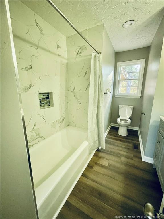 full bathroom featuring shower / bath combination with curtain, vanity, a textured ceiling, wood-type flooring, and toilet