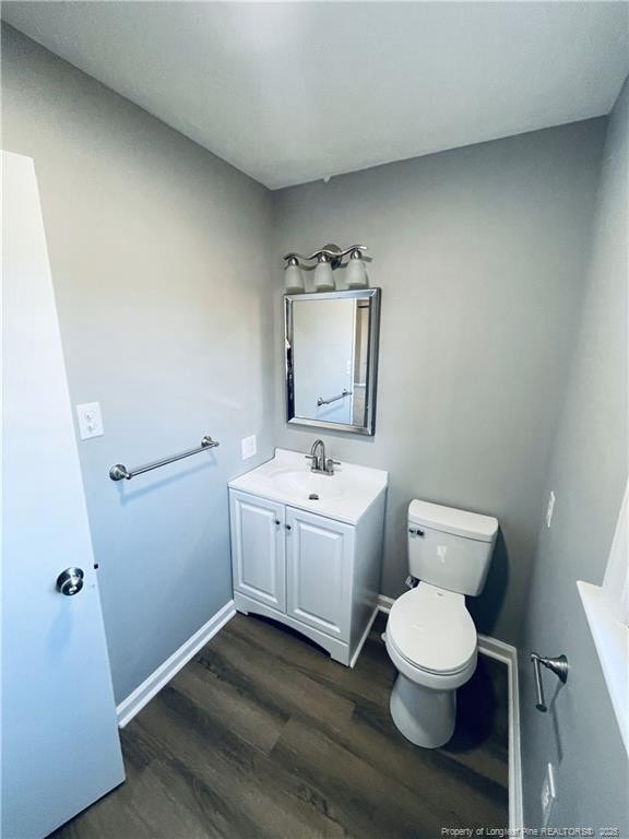 bathroom with toilet, vanity, and hardwood / wood-style flooring