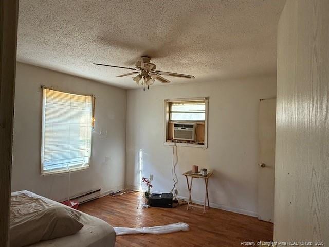 sitting room with a textured ceiling, cooling unit, ceiling fan, a baseboard heating unit, and wood-type flooring