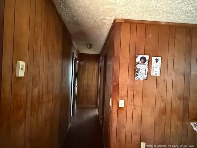 corridor featuring a textured ceiling and wood walls