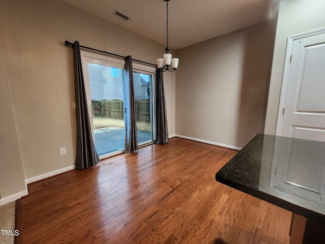 unfurnished dining area featuring wood-type flooring and an inviting chandelier