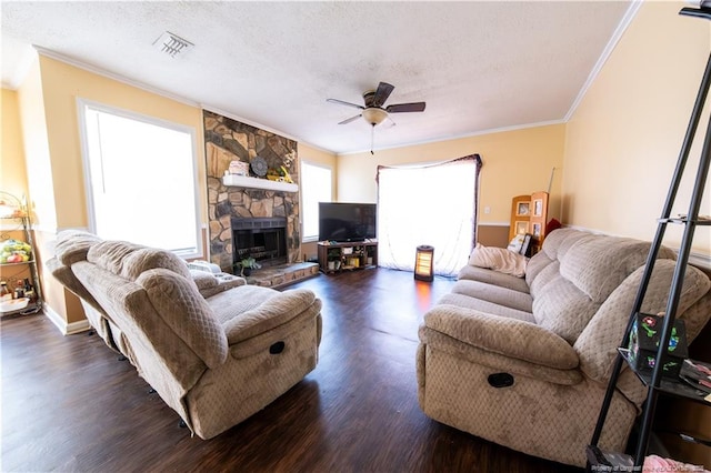 living room featuring ornamental molding, a textured ceiling, ceiling fan, dark wood-type flooring, and a fireplace