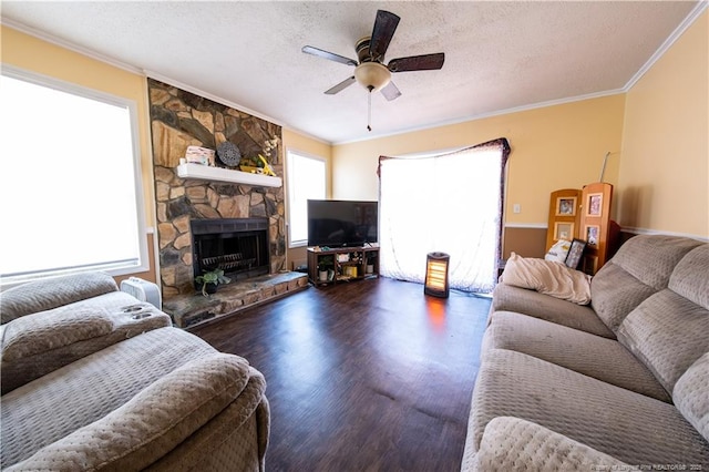 living room with ceiling fan, a healthy amount of sunlight, a stone fireplace, and a textured ceiling