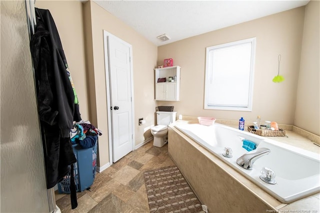 bathroom featuring a relaxing tiled tub and toilet