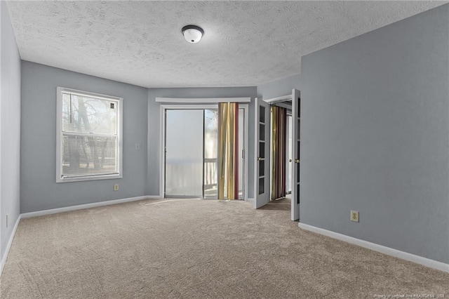 spare room with light colored carpet, a healthy amount of sunlight, and a textured ceiling