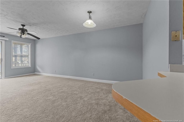 carpeted spare room featuring a textured ceiling and ceiling fan