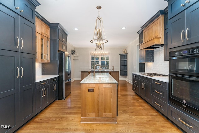 kitchen featuring backsplash, appliances with stainless steel finishes, a kitchen island with sink, and hanging light fixtures