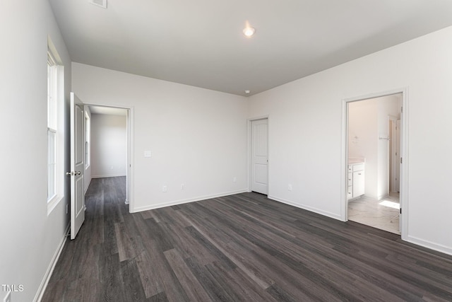 unfurnished bedroom featuring dark hardwood / wood-style flooring, ensuite bathroom, and a closet