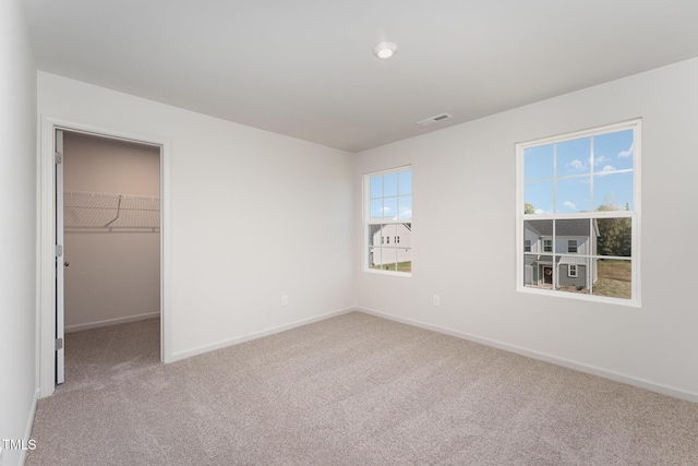 unfurnished bedroom featuring a walk in closet, carpet floors, and a closet