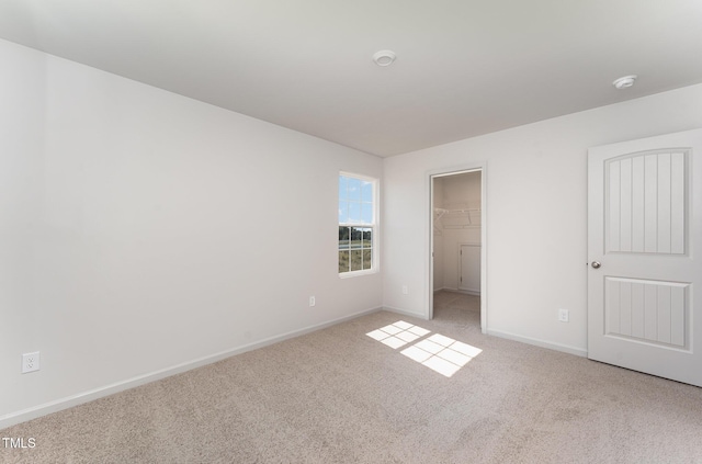 unfurnished bedroom with a spacious closet, light carpet, and a closet