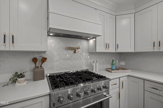 kitchen featuring white cabinets, decorative backsplash, high end stove, and premium range hood