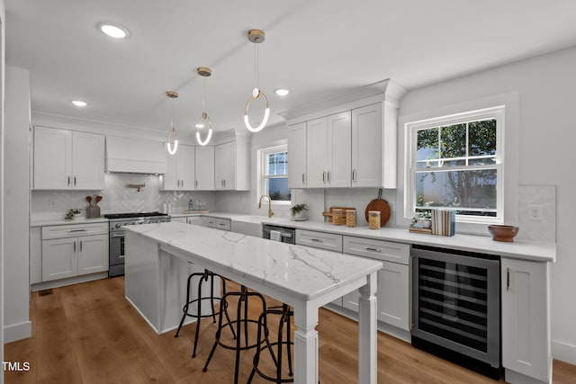 kitchen featuring stainless steel appliances, hanging light fixtures, beverage cooler, decorative backsplash, and white cabinets