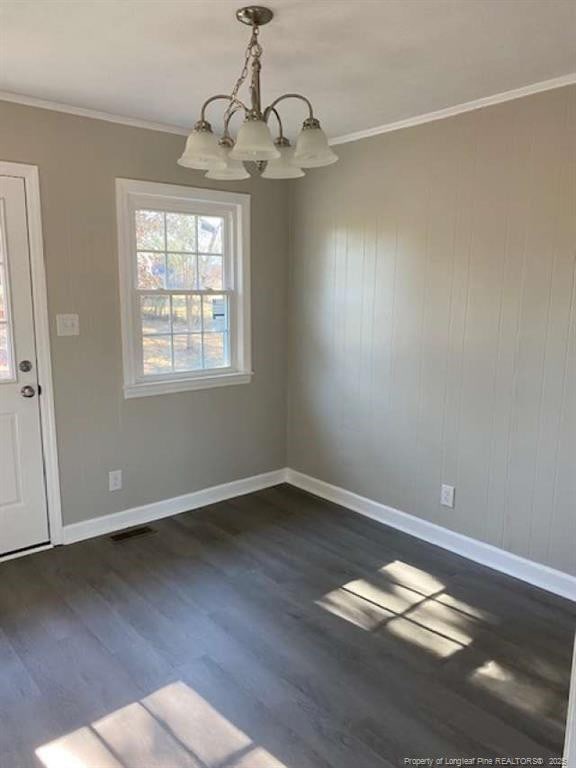 unfurnished dining area featuring crown molding, dark hardwood / wood-style floors, and an inviting chandelier