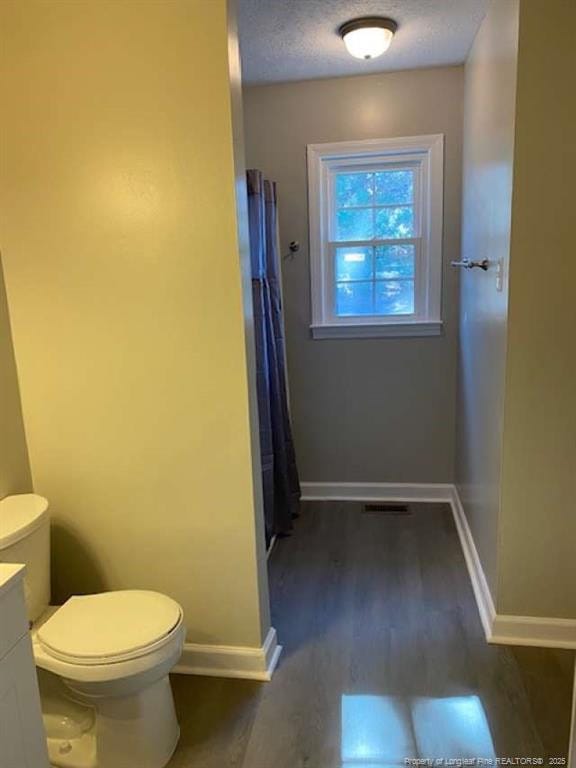 bathroom featuring hardwood / wood-style floors, vanity, toilet, and a textured ceiling