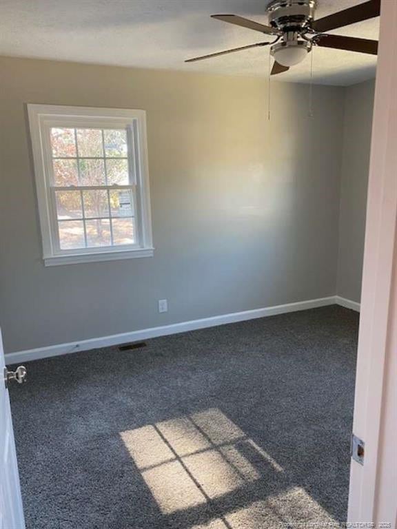 unfurnished room featuring ceiling fan and dark colored carpet