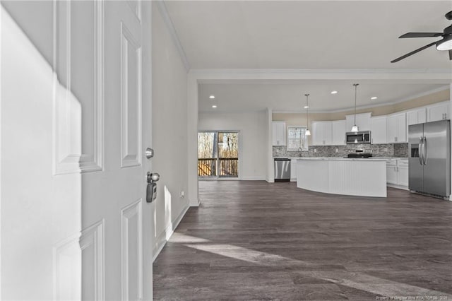 kitchen featuring white cabinetry, stainless steel appliances, pendant lighting, a kitchen island, and ornamental molding