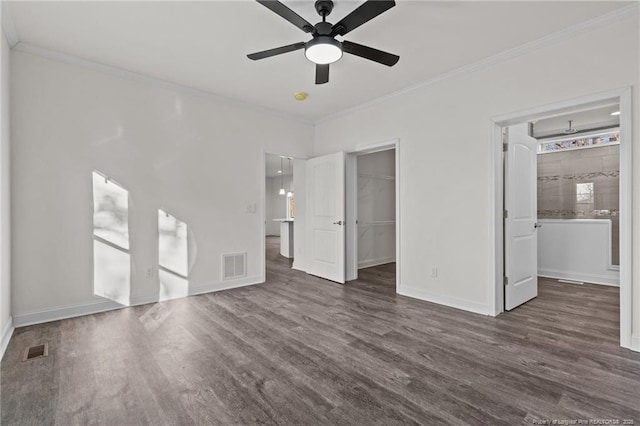 unfurnished bedroom featuring dark wood-type flooring, a walk in closet, crown molding, ceiling fan, and a closet