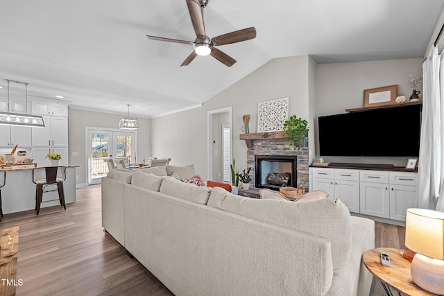 living room with hardwood / wood-style flooring, ceiling fan, lofted ceiling, and a fireplace