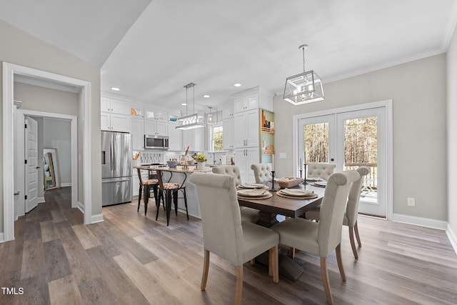 dining area featuring french doors, light hardwood / wood-style flooring, lofted ceiling, and crown molding