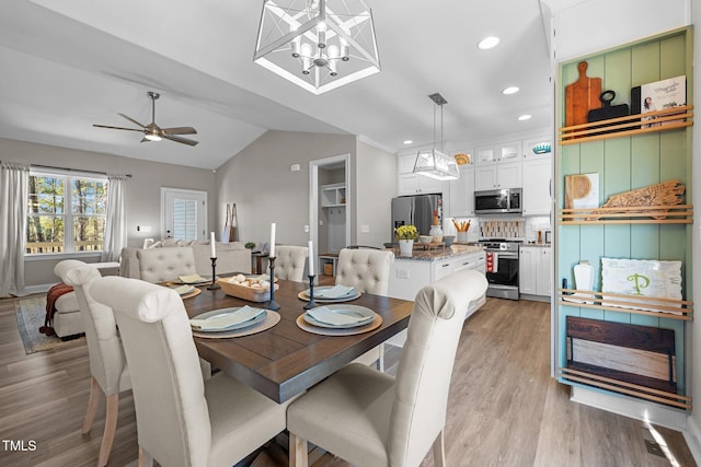 dining room featuring ceiling fan with notable chandelier, lofted ceiling, and light hardwood / wood-style flooring