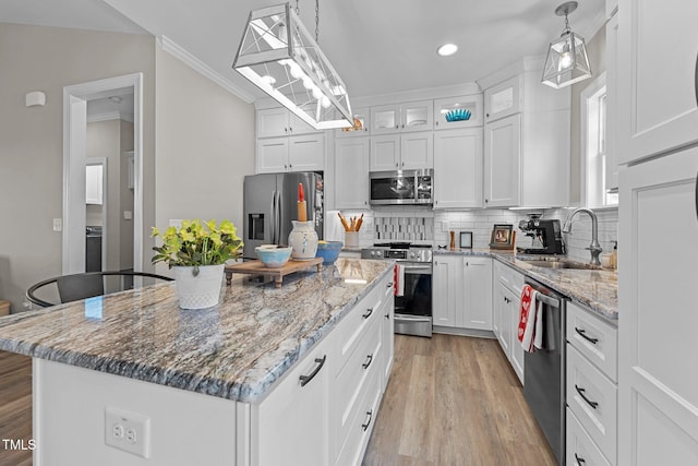 kitchen featuring appliances with stainless steel finishes, white cabinetry, a kitchen island, and sink