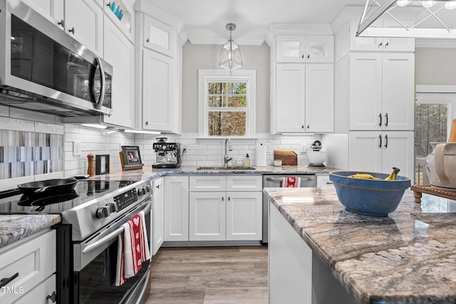 kitchen with white cabinets, hanging light fixtures, sink, light stone countertops, and appliances with stainless steel finishes