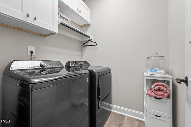 laundry room featuring hardwood / wood-style floors, washer and clothes dryer, and cabinets