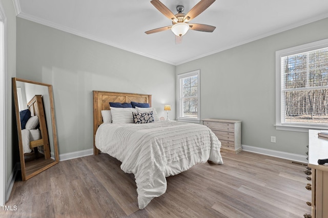 bedroom featuring multiple windows, wood-type flooring, ceiling fan, and ornamental molding